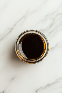 This image shows a small airtight glass jar filled with the rich autumn salad dressing, sealed and ready to be refrigerated until use.