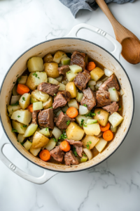 layering-carrots-onions-and-potatoes-over-lamb-in-dutch-oven
