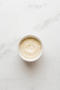 This image shows the prepared lemon garlic aioli being chilled in the refrigerator, allowing the flavors to meld and the texture to set before serving.