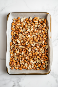 This image shows roasted nuts spread out on a baking sheet, cooling down before being added to the broccoli salad.