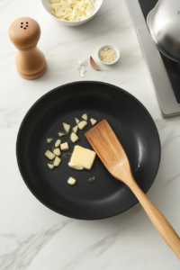 This image shows garlic gently sautéing in a skillet with golden butter, creating a fragrant base for the sauce.