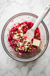 This image shows a mixing bowl with softened cream cheese and asiago cheese waiting to be combined with the vibrant cranberry jalapeño mixture.