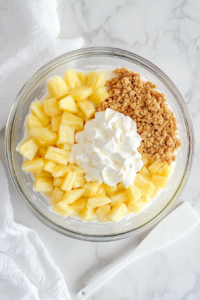 mixing-cool-whip-pudding-mix-and-crushed-pineapple-in-a-glass-bowl