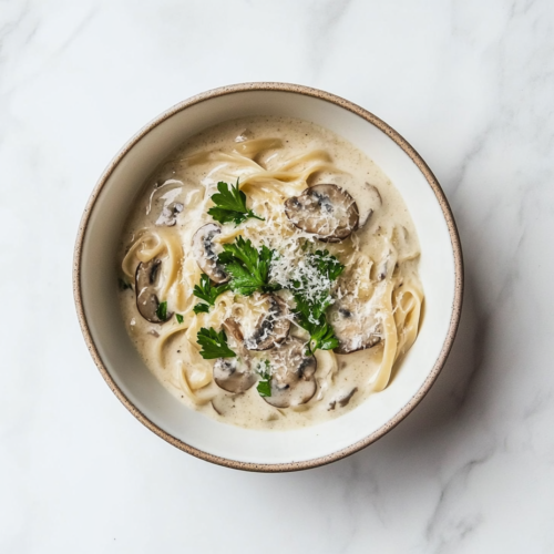 mushroom-alfredo-in-creamy-white-sauce-served-in-a-ceramic-bowl-topped-with-fresh-cilantro