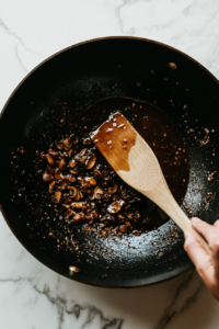 This image shows hands or utensils tossing the carrots in the bowl until they are evenly coated with the flavorful mixture.