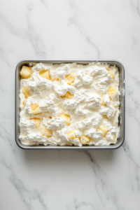 This image shows a fully assembled pineapple cake resting in a refrigerator, allowing the topping to chill and set for a cool, refreshing dessert.