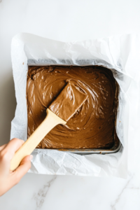 This image shows the thick and spiced Parkin batter being poured into a cake tin, ensuring an even distribution before baking.