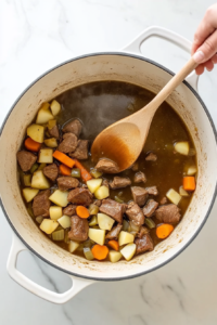 pouring-thickened-stock-into-dutch-oven-filled-with-lamb-and-vegetables