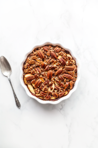 This image shows the baked crisp cooling and being served, its sweet pecan topping glistening and the apples tender and juicy underneath.