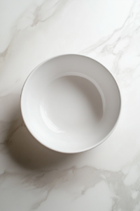 This image shows a medium-sized shallow white bowl placed on a counter, ready to be filled with vibrant salad ingredients.