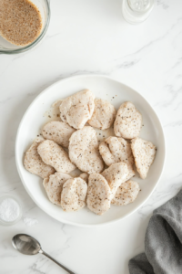 This image shows oval-shaped chicken patties formed from a seasoned mixture, neatly arranged on a plate over white marble.