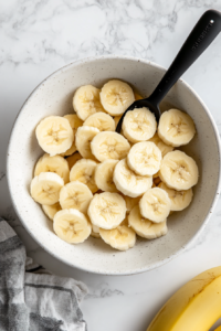 sliced-bananas-being-tossed-in-lemon-juice-to-prevent-browning-before-layering