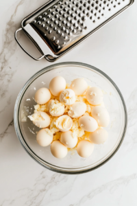 This image shows a grater in action, turning hard-boiled eggs into delicate, fluffy shreds, perfect for a creamy egg salad base.