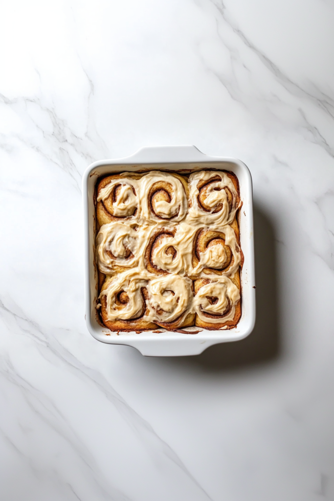 spreading-the-warm-cream-over-the-cinnamon-roll-serving