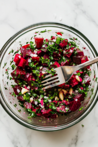 This image shows the beetroot salad mixture being thoroughly stirred, ensuring all ingredients are evenly coated and well combined.