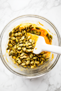 stirring-pumpkin-seeds-into-sweet-honey-mixture-until-well-coated