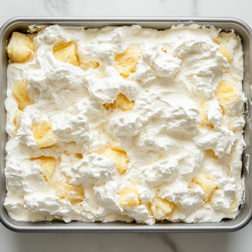 sugar-free-pineapple-cake-in-baking-tray-topped-with-cream-and-infused-pineapple