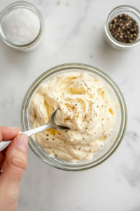 tasting-aioli-from-spoon-and-adjusting-seasoning-with-salt-pepper-and-additional-lemon-if-needed