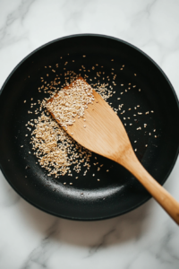 toasting-sesame-seeds-in-a-dry-pan-until-golden-brown-for-enhanced-flavor-top-down-shot