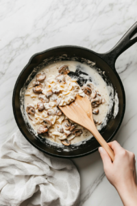 tossing-drained-pasta-into-the-pan-to-coat-evenly-with-mushroom-alfredo-sauce