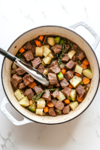 transferring-second-batch-of-lamb-into-dutch-oven-over-vegetables