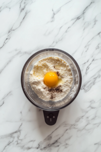 adding-egg-vanilla-to-crumb-mixture-in-food-processor
