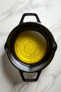 black-dutch-oven-with-olive-oil-heating-on-white-marble-countertop