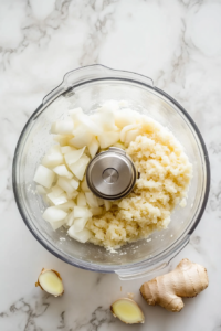 blending-onion-garlic-ginger-paste-in-glass-food-processor-white-marble
