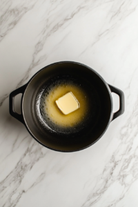 butter-melting-in-large-black-soup-pot-on-white-marble-top-3