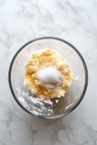 buttercream-mixture-being-whisked-in-glass-bowl-on-marble