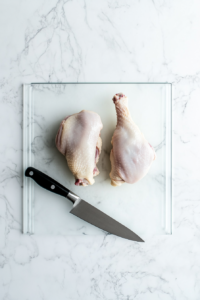 butterfly-chicken-breasts-on-white-marble-glass-cutting-board