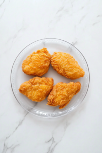 cooked-chicken-breasts-resting-on-glass-plate-white-marble