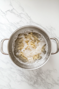 cooking-fettuccine-pasta-in-stainless-steel-pot-over-white-marble