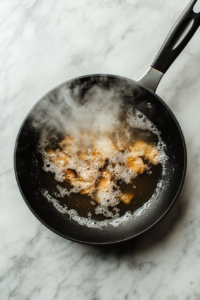 deglazing-chicken-broth-black-skillet-marble-background