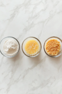 This image shows a clean dipping station with bowls of flour, egg-milk mixture, and breadcrumbs on a white marble surface.