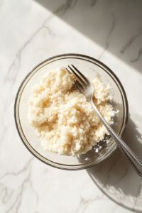 fluffed-white-rice-in-glass-bowl-with-fork-on-white-marble