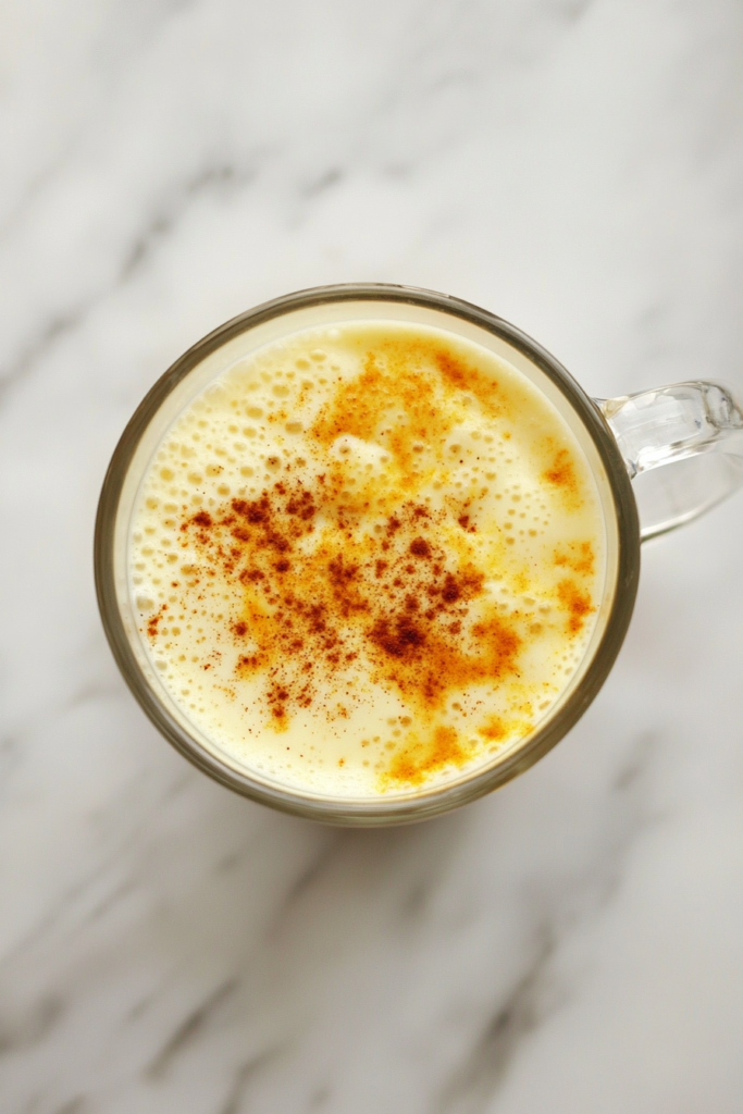golden-milk-latte-in-clear-glass-mug-on-white-marble