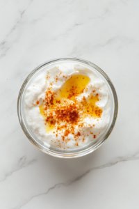 greek-yogurt-sauce-ingredients-in-small-glass-bowl-on-white-marble