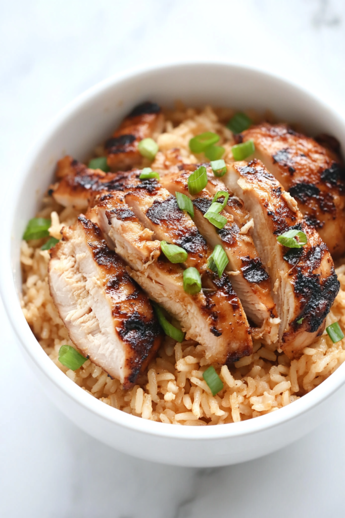 This image shows Hawaiian grilled chicken served over coconut rice in a white bowl on a spotless white marble surface.