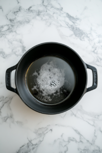 heating-oil-in-black-dutch-oven-on-white-marble-for-keto-chicken-dumplings