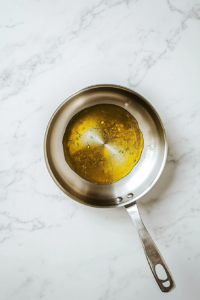 heating-olive-oil-in-stainless-steel-frying-pan-white-marble