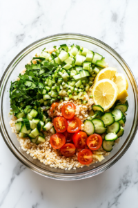 This image shows lemon juice, salt, and black pepper added to the brown rice and vegetables in a clear glass bowl on a white marble cooktop.