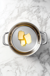 melting-butter-in-large-aluminum-pot-on-white-marble