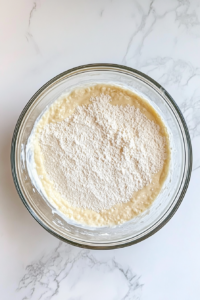 mixing-flour-butter-milk-yolks-and-vanilla-in-glass-bowl-for-castella