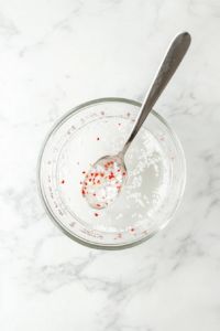 mixing-pickle-brine-in-glass-measuring-cup-on-white-marble