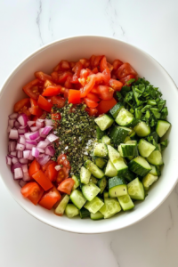 oregano-and-salt-sprinkled-on-greek-salad-in-white-ceramic-bowl