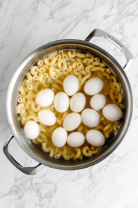 pot-of-elbow-macaroni-and-eggs-boiling-on-white-marble