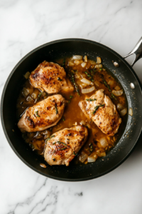 pouring-chicken-stock-into-black-skillet-on-white-marble