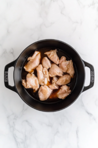 raw-chicken-in-black-dutch-oven-with-asian-sauce-on-white-marble