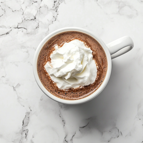 This image shows a luxurious serving of French hot chocolate in a white ceramic mug, topped with a fluffy dollop of whipped cream, placed elegantly on a clean white marble countertop with no background distractions.